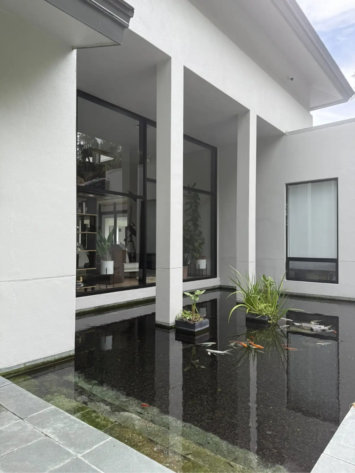 Clean picture windows reflecting a courtyard and koi pond