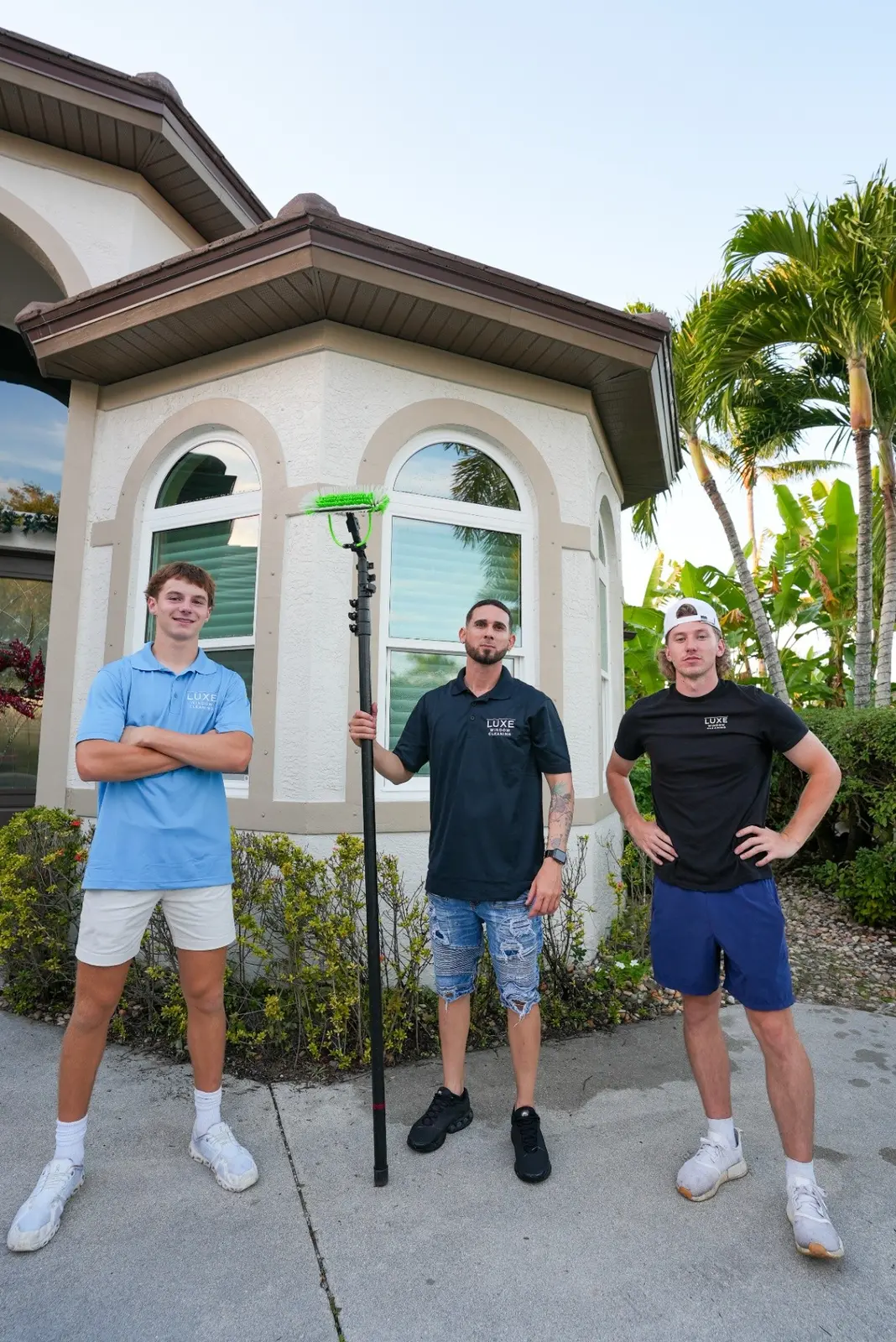 Three window-cleaning team members with their equipment outside a Southwest Florida home